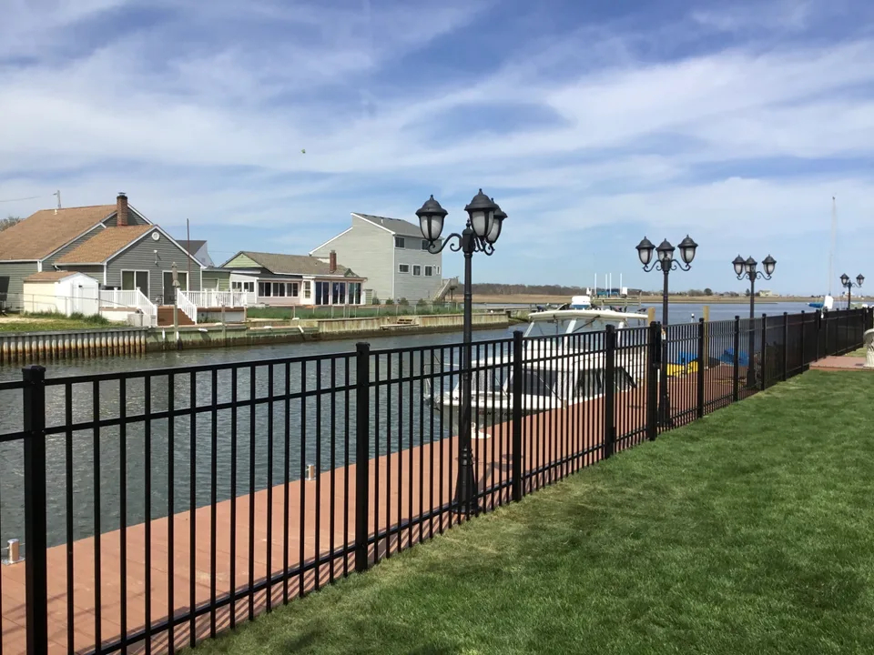Long run of four-foot black aluminum fence along a Mastic Beach, New York waterfront bulkhead.