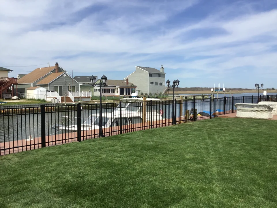 Wide residential view of a four-foot black aluminum waterfront fence in Mastic Beach, New York.