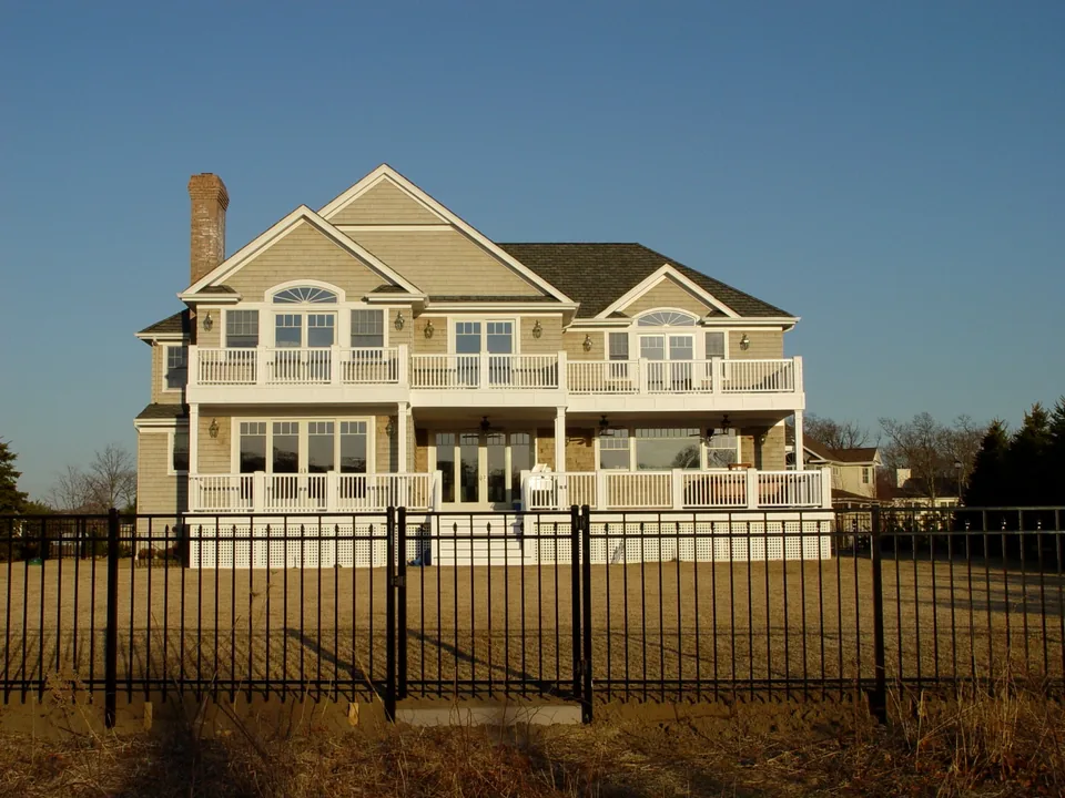 Four-foot black aluminum fence defining the residential property boundary beside a house in Center Moriches, New York.