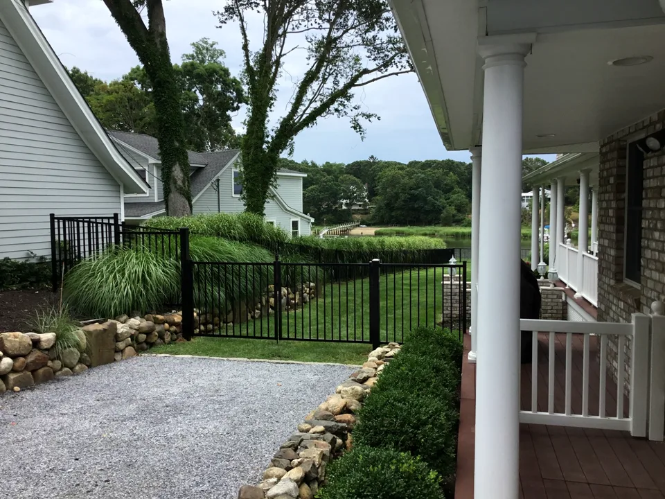 Black aluminum walk gate within a four-foot backyard perimeter fence in Mattituck, New York.