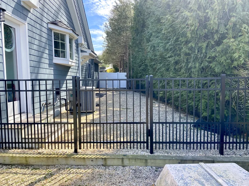 Four-foot black aluminum fence with closely spaced puppy pickets along a Sag Harbor, New York side yard.