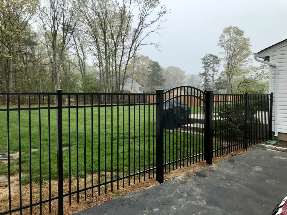Five-foot black Style 202 aluminum fence with an arched walk gate in Bellport, New York.