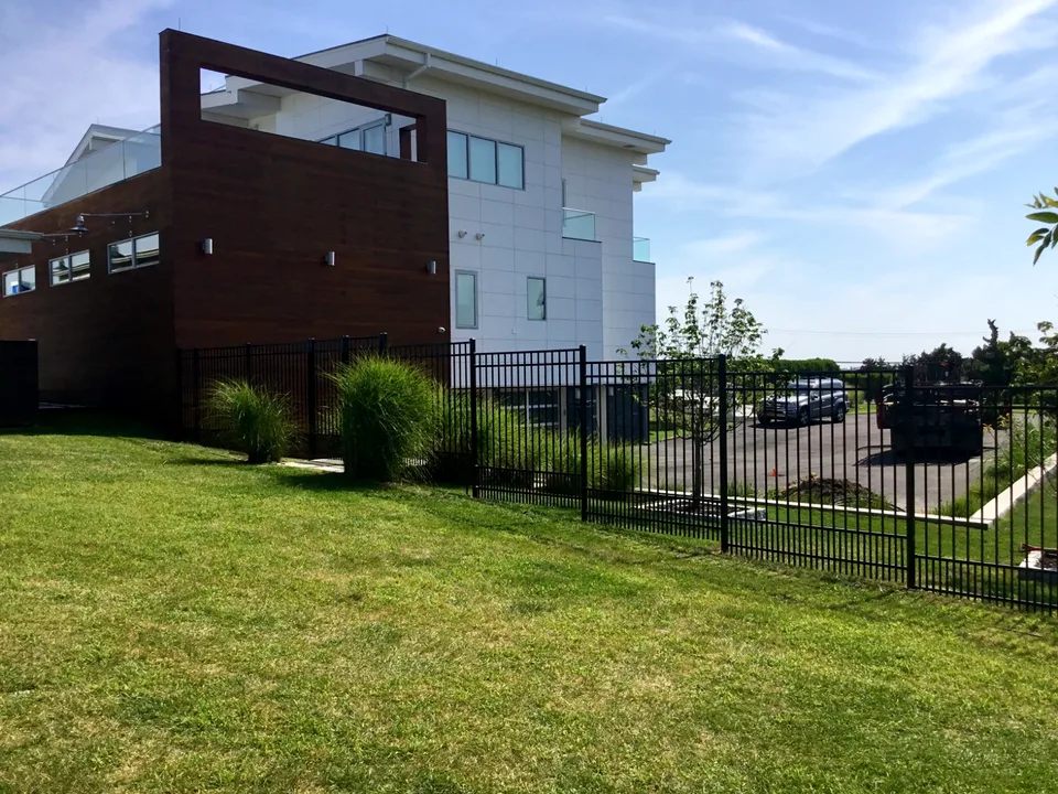 Six-foot black aluminum fence following a grade change beside a Westhampton, New York residence.