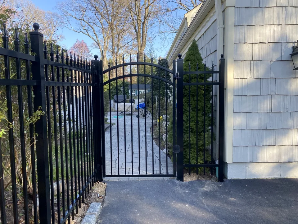 Arched black aluminum walk gate within a six-foot Jerith Estate fence in Mount Sinai, New York.