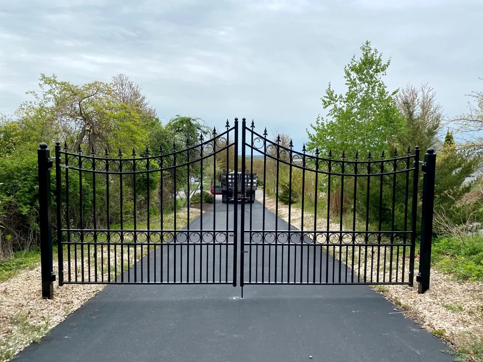 Black ornamental steel estate driveway gate with a decorative arched profile in Calverton, New York.