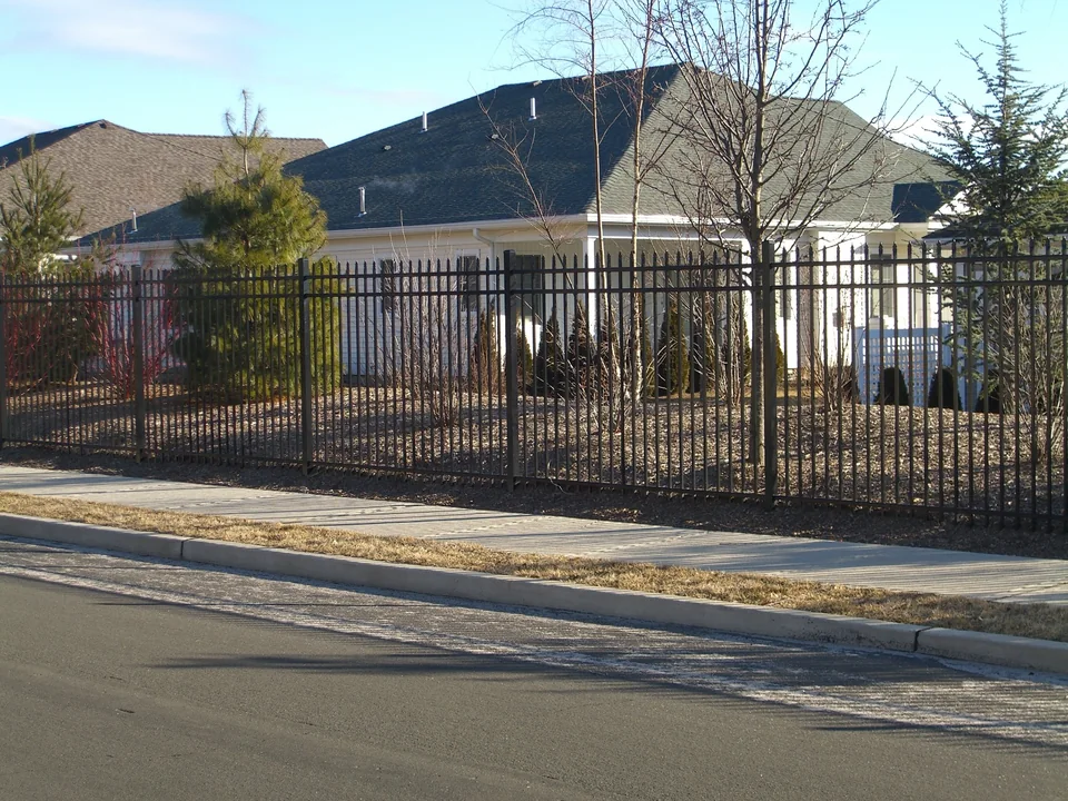Six-foot black commercial aluminum fence along the perimeter of a 55-and-older residential community in Stony Brook, New York.