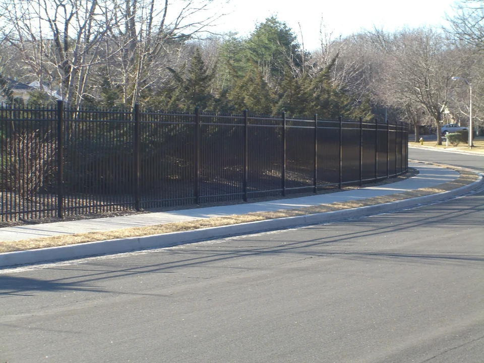 Six-foot black commercial aluminum fencing continuing around a corner at a Stony Brook 55-and-older residential community.