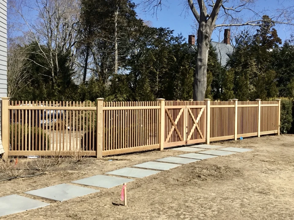 Long run of custom cedar picket fencing with capped posts in Southampton, NY