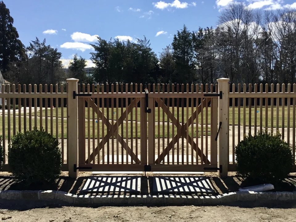 Custom cedar double gate framed by landscaping at a Southampton property