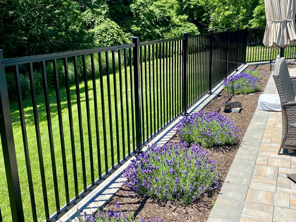 Four-foot black aluminum fence integrated with a raised landscaped pool patio in Miller Place, New York.