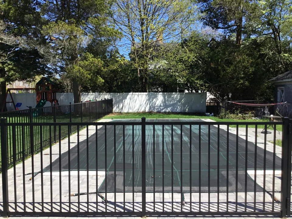Black aluminum gate within a four-foot pool fence in Bayport, New York.