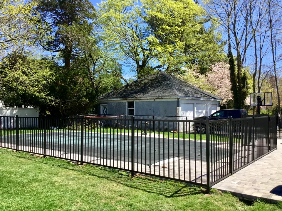 Black aluminum pool fence integrated with mature landscaping in Bayport, New York.