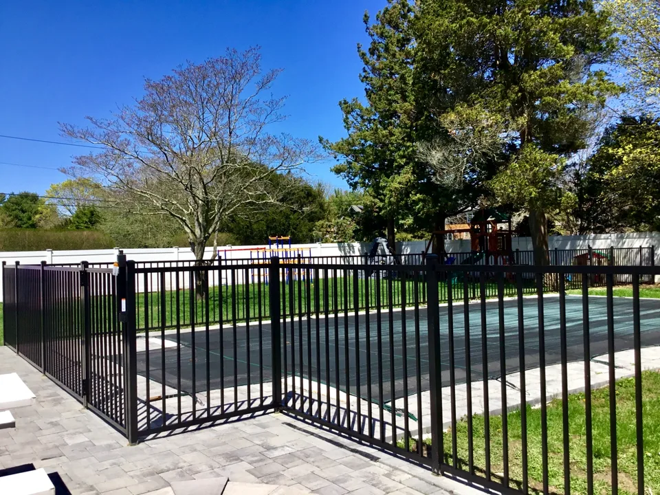 Four-foot black aluminum fence following the perimeter of a residential pool in Bayport, New York.