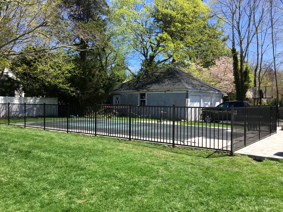 Four-foot black aluminum fence beside a landscaped residential pool in Bayport, New York.