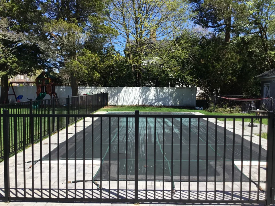 Four-foot black aluminum pool fence shown across a landscaped Bayport residential property.