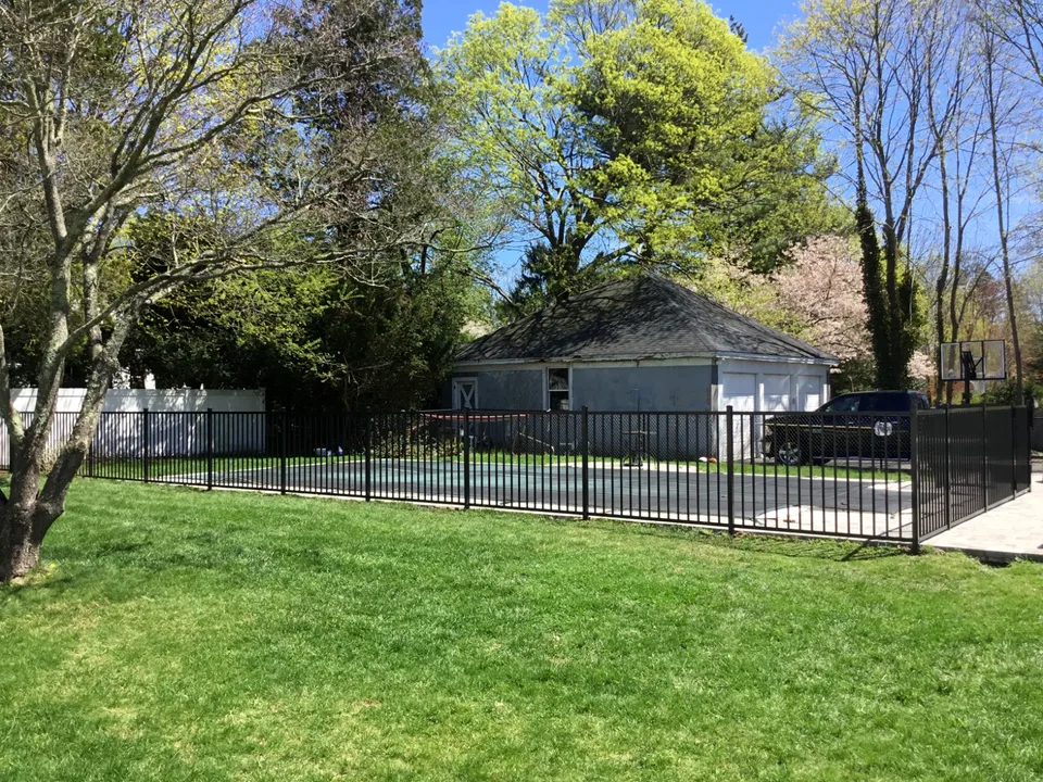 Wide view of a four-foot black aluminum pool fence in Bayport, New York.