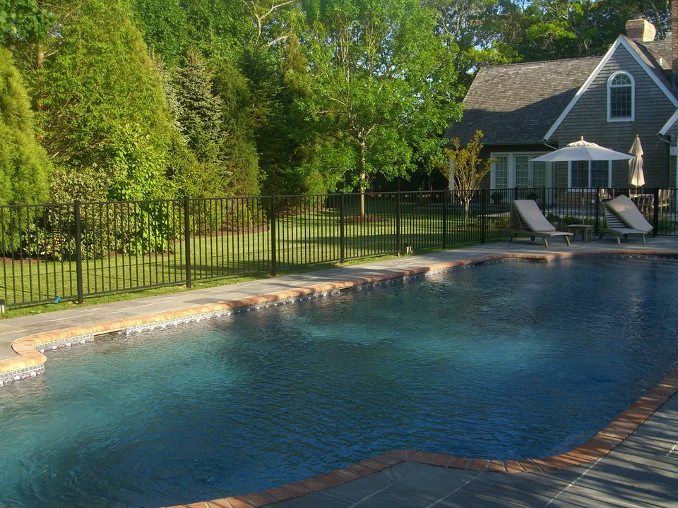 Four-foot black aluminum fence defining the perimeter of a residential pool area in East Hampton, New York.