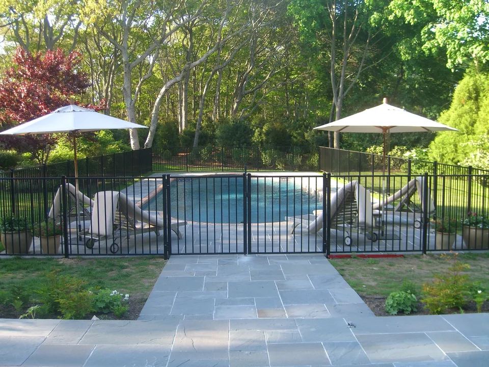Black aluminum pool fence extending beside a swimming pool in East Hampton, New York.