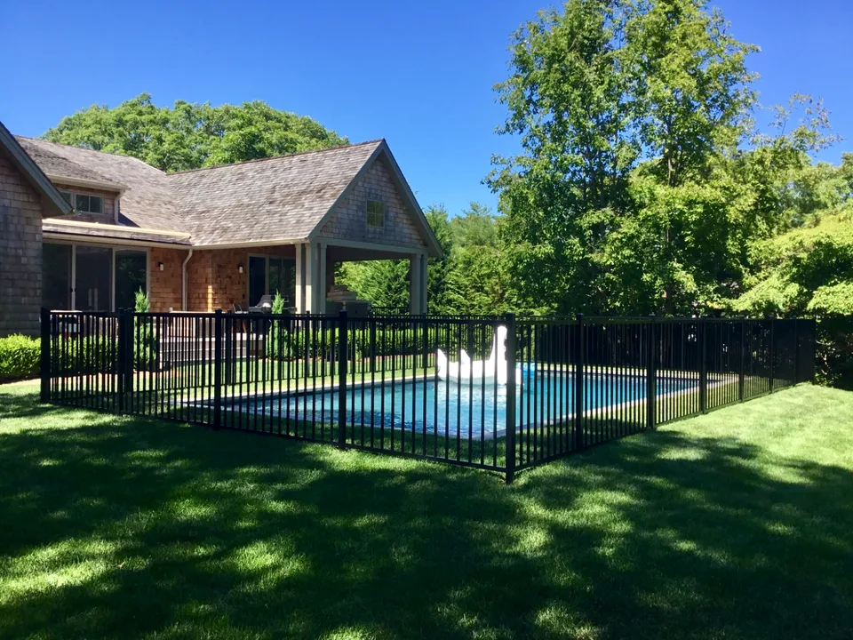 Black aluminum pool fence running beside a residential pool in The Springs, East Hampton, New York.