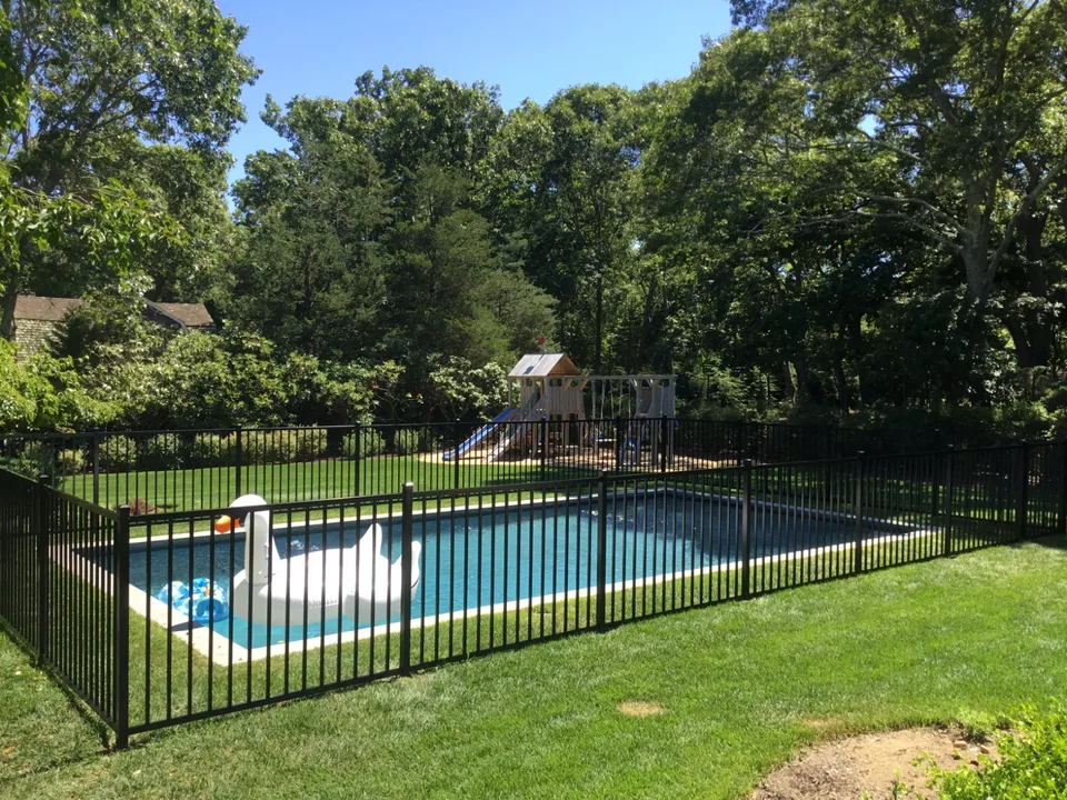 Black aluminum pool fence shown across a landscaped residential property in The Springs, East Hampton, New York.