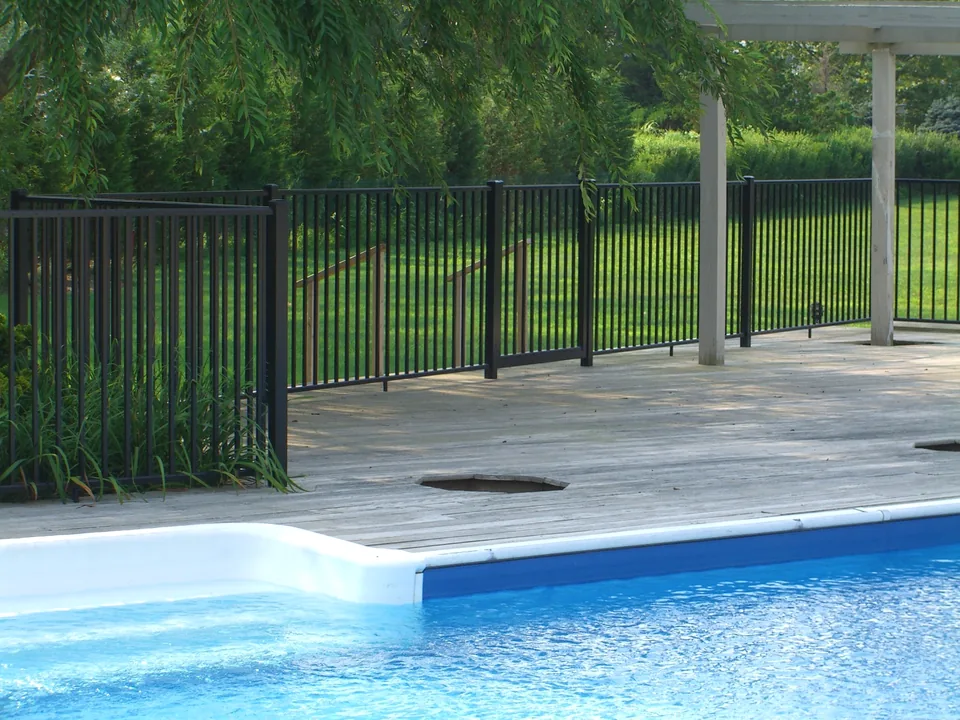Four-foot black aluminum pool fence extending along a wood deck beside a pool in Southampton, New York.
