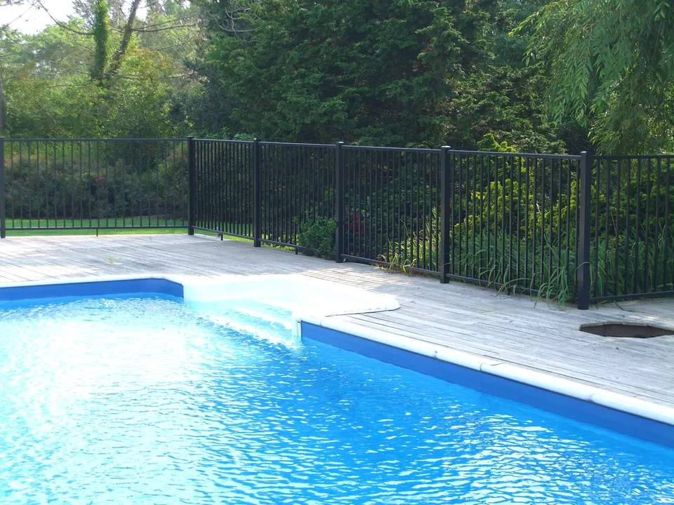 Four-foot black aluminum pool fence enclosing a pool from a wood deck in Southampton, New York.