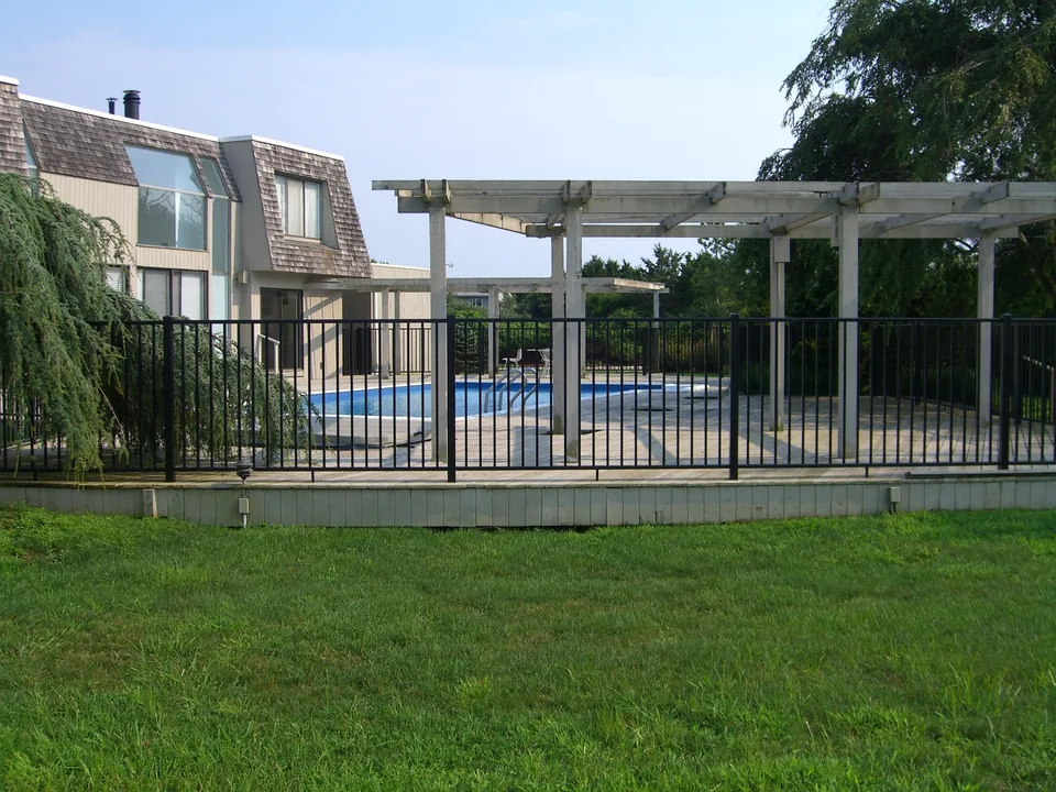 Wide view of a four-foot black aluminum pool fence installed on a wood deck in Southampton, New York.