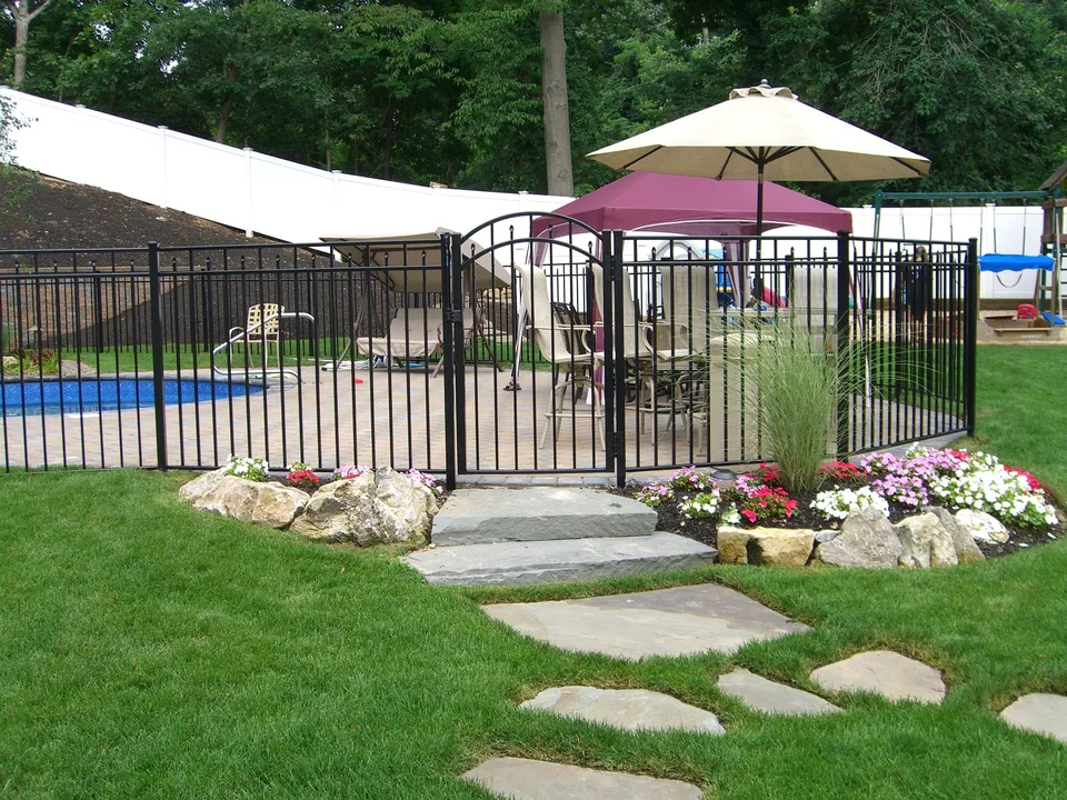 Black aluminum gate within a 54-inch pool fence beside a residential pool in Dix Hills, New York.