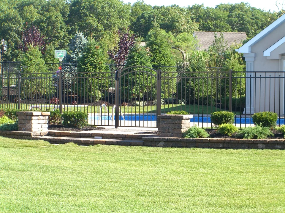 54-inch black aluminum pool fence enclosing a landscaped residential pool area in Miller Place, New York.