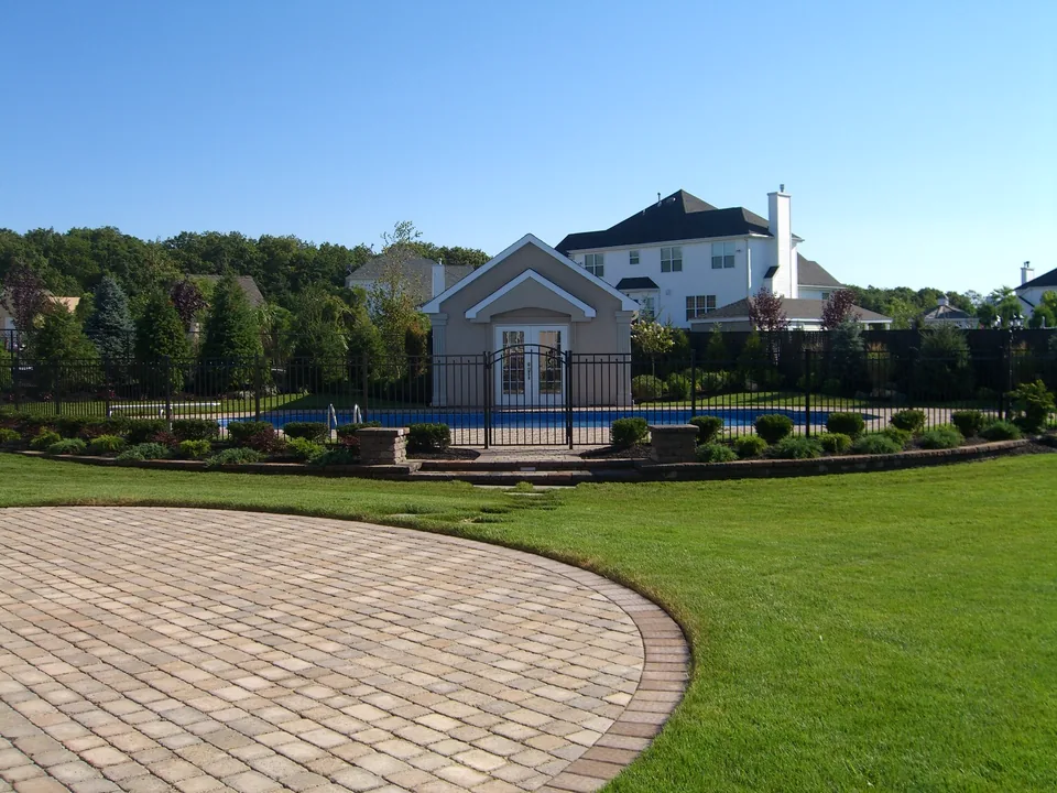 Wide property view of a 54-inch black aluminum pool fence surrounding an inground pool in Miller Place, New York.