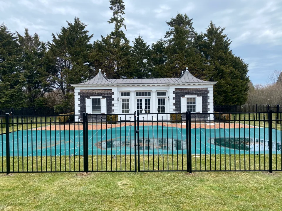 Centered gate within a 54-inch black aluminum pool fence in Southampton, New York.