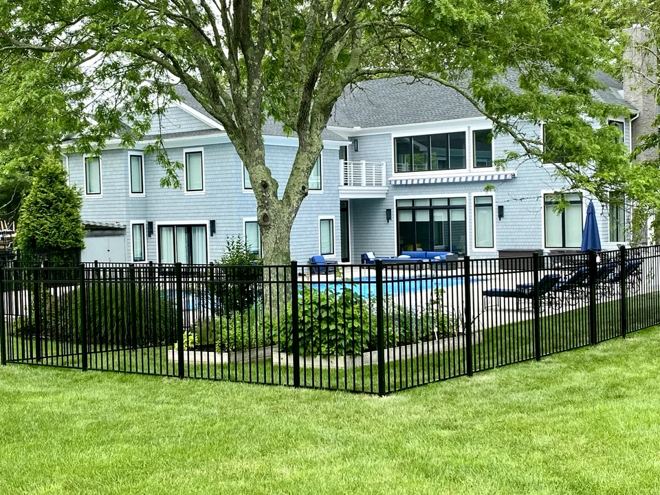 Fifty-four-inch black Style 202 aluminum fence wrapping around landscaped garden areas beside a pool in Remsenburg, New York.