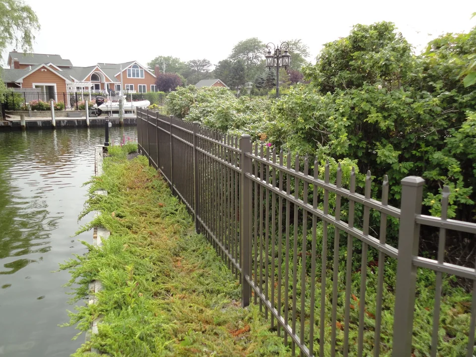 Aluminum estate-style fence installed beside a canal bulkhead in East Islip, New York
