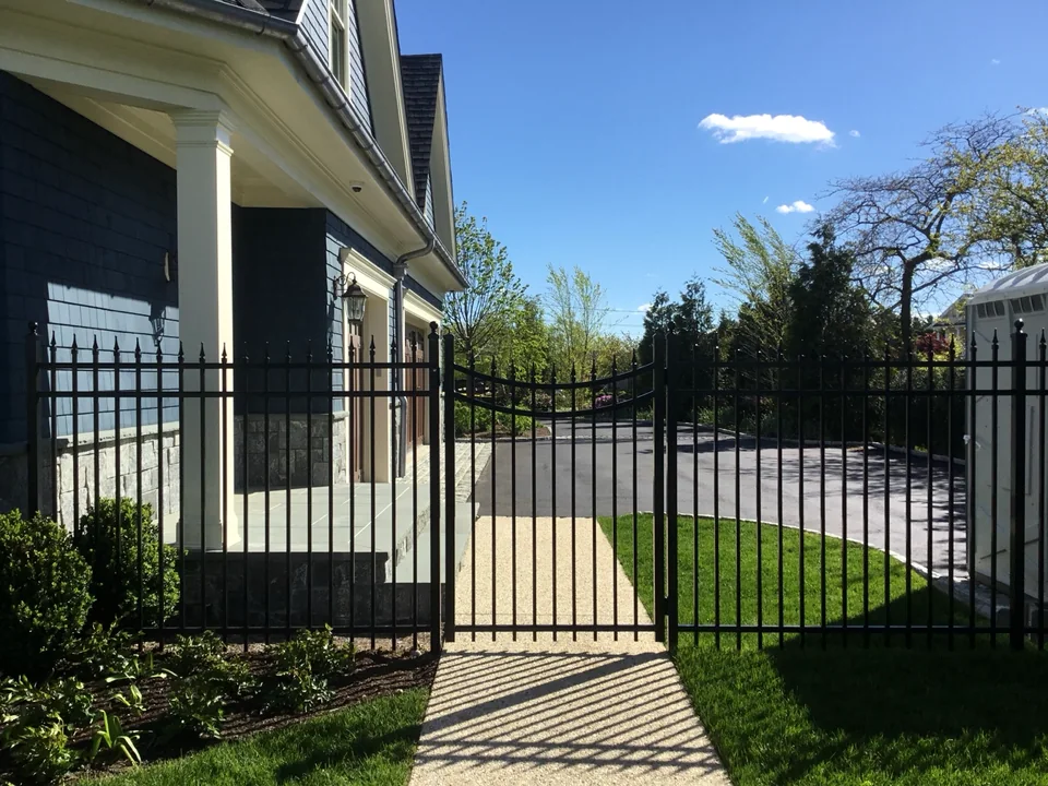 Decorative black aluminum spear-top gate beside the driveway at a custom East Islip home