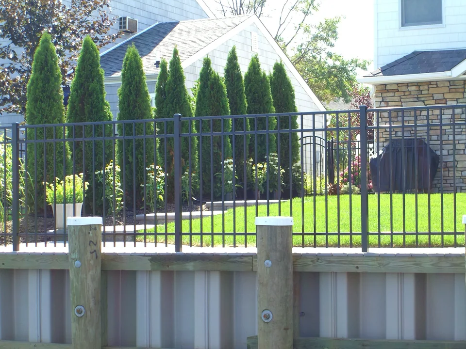 Straight waterfront elevation of black aluminum fence above a wood bulkhead in Seaford, New York