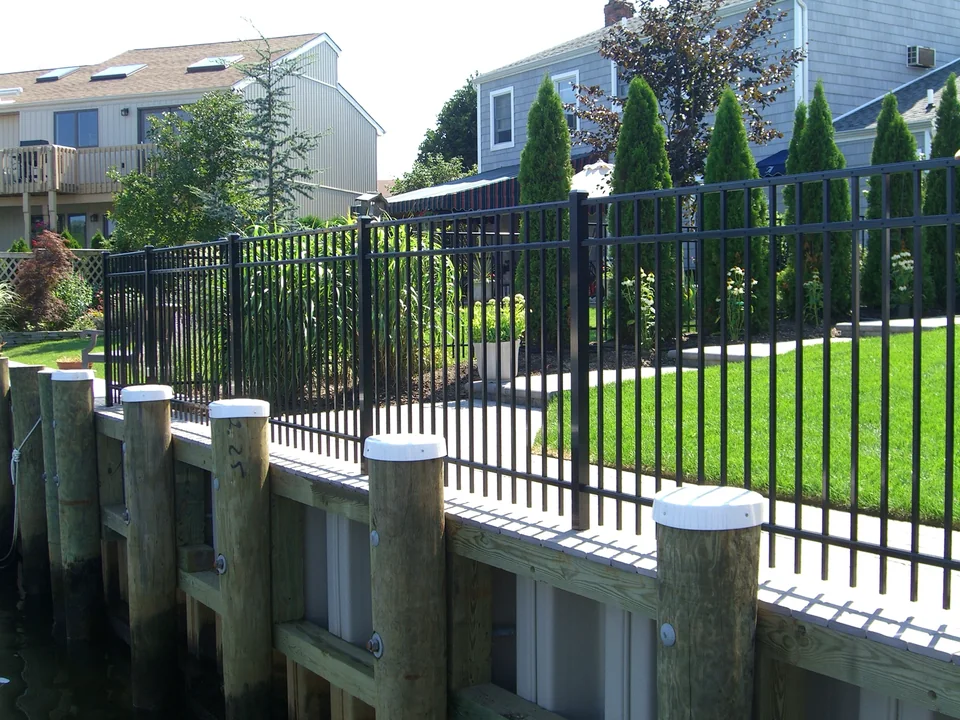 Water-side view of black aluminum fence installed along a wood deck bulkhead in Seaford, New York
