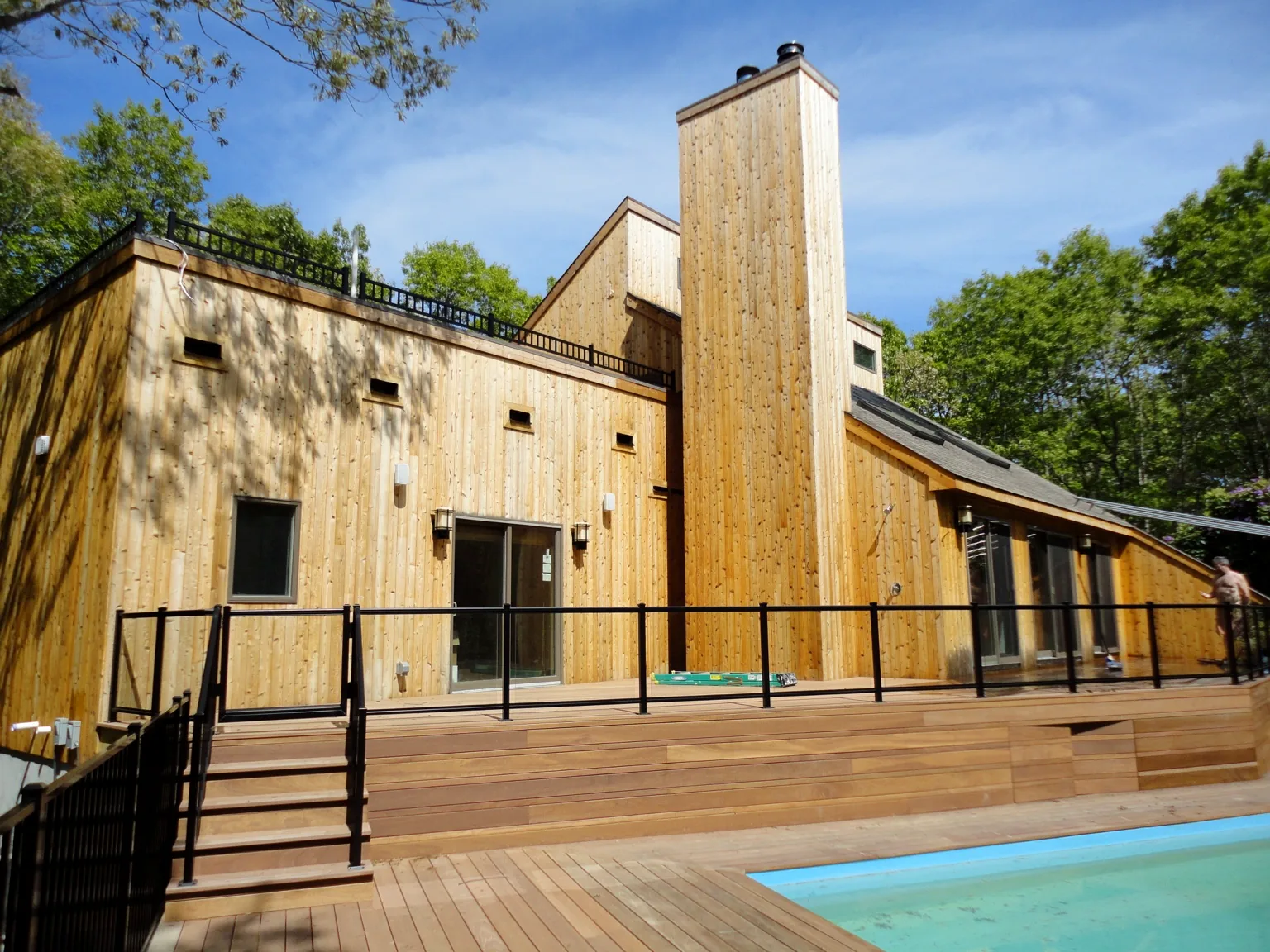 Wide view of the Southampton home, elevated wood deck and custom aluminum-framed glass railing above the pool