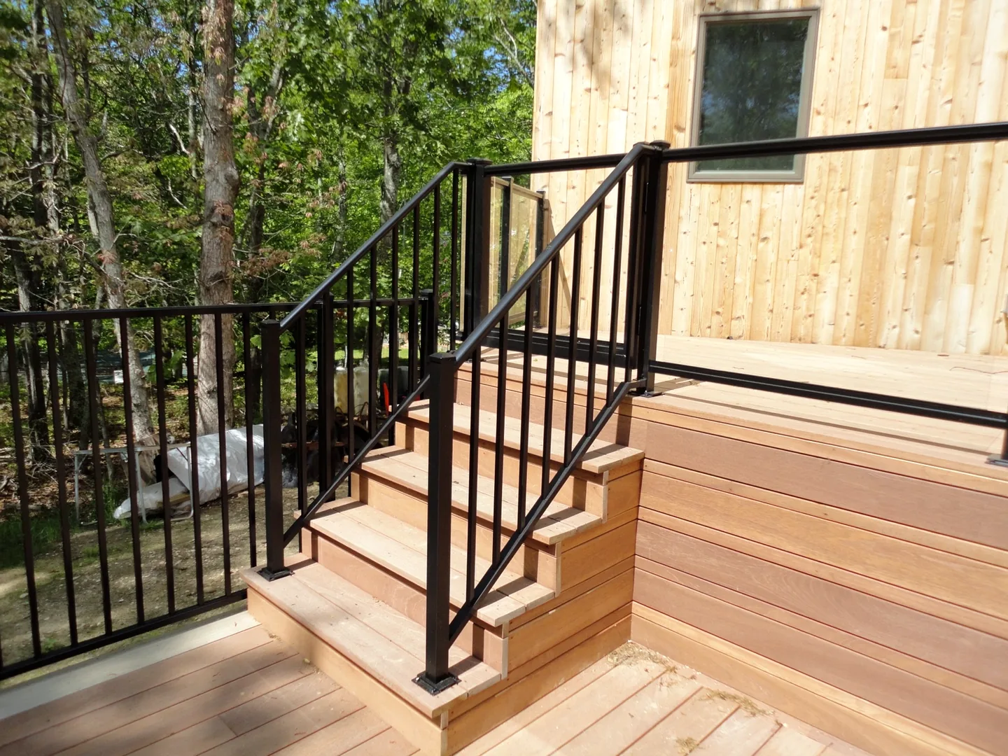 Black aluminum stair railing transitioning from the glass railing system on the Southampton wood deck