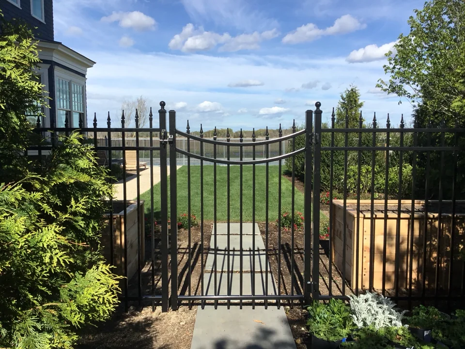 Decorative aluminum garden gate opening toward the lawn at an East Islip waterfront home