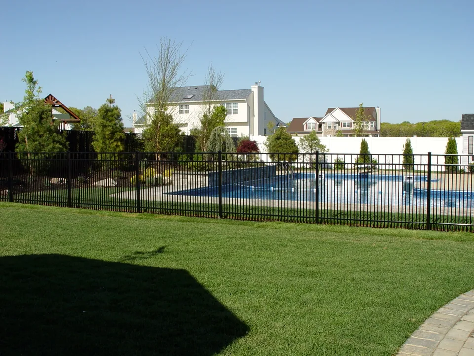 Wide view of the black aluminum pool enclosure and landscaped backyard in Miller Place, New York