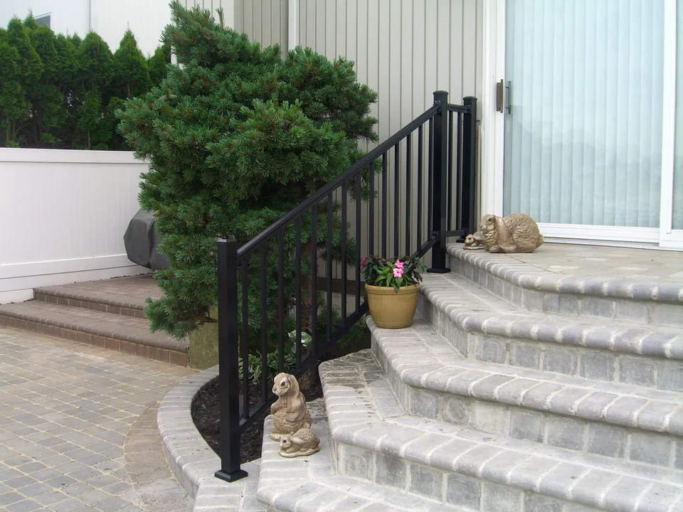 Black aluminum stair railing following curved masonry steps at a Seaford waterfront home