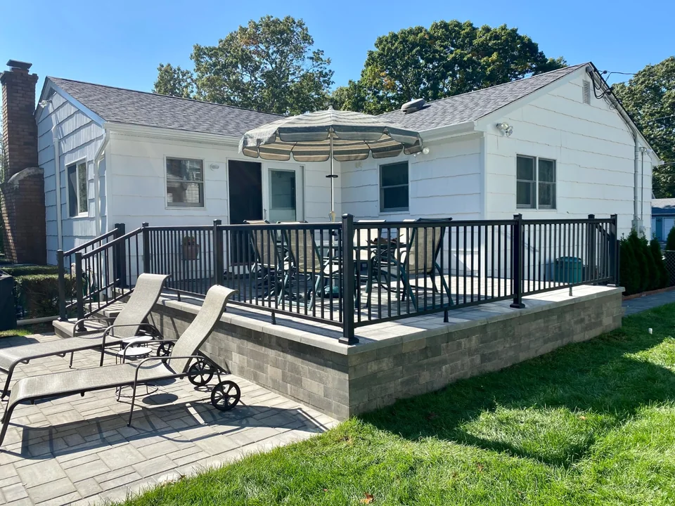 Black aluminum railing around a backyard patio at a Bellport, New York home