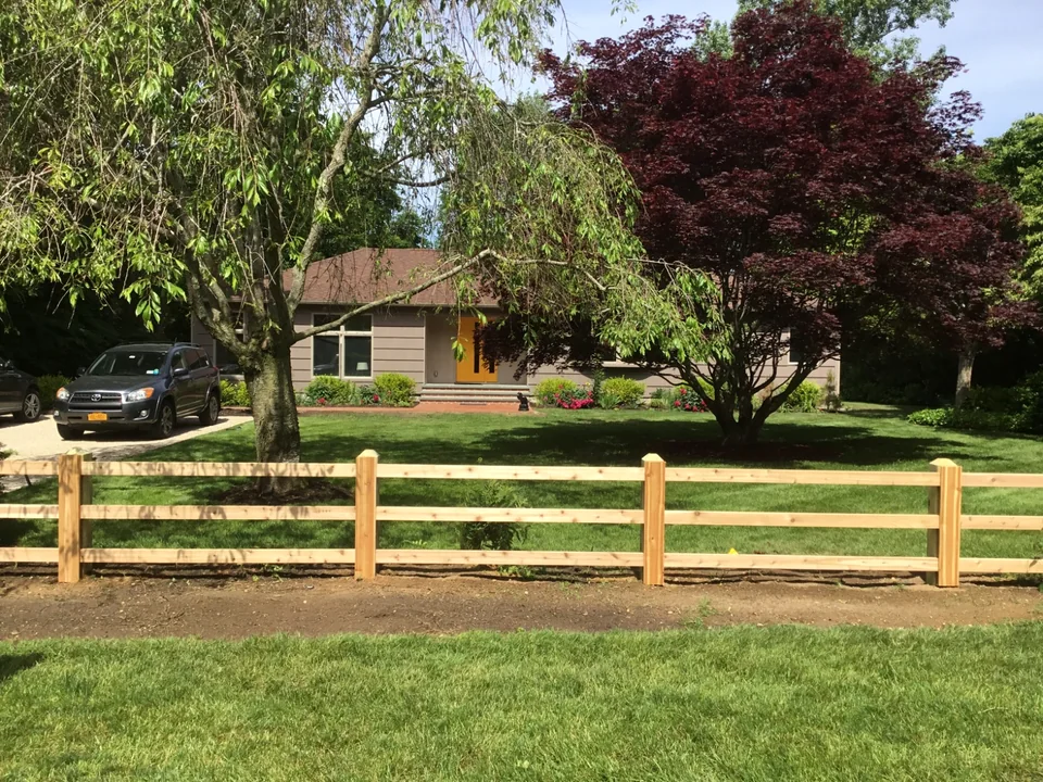 Custom three-rail board fence across a Bellport, New York front yard.