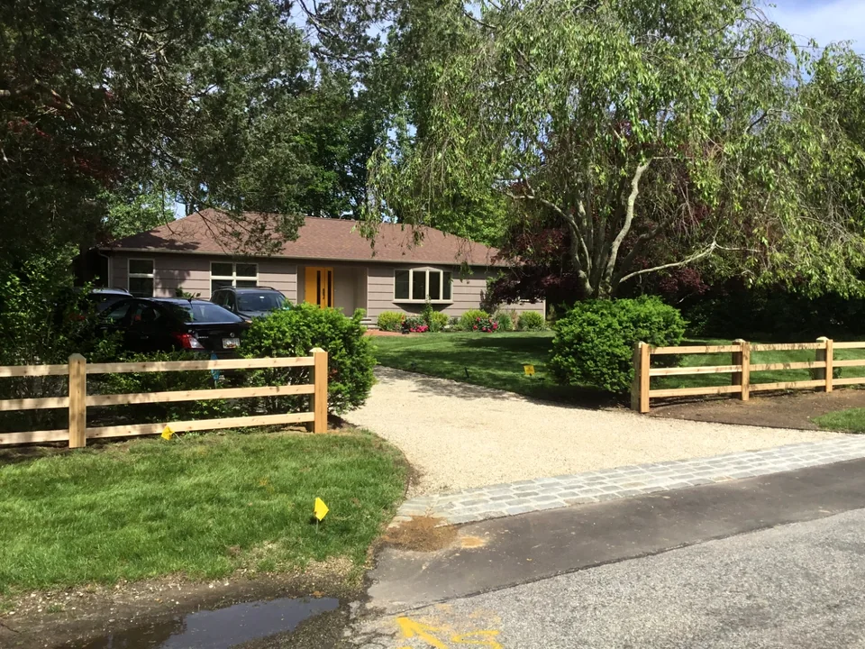 Three-rail board fence meeting a driveway in Bellport, New York.