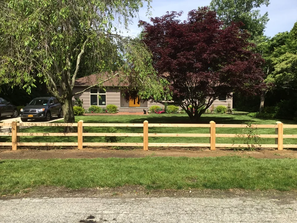 Street-side view of a custom three-rail board fence in Bellport, New York.
