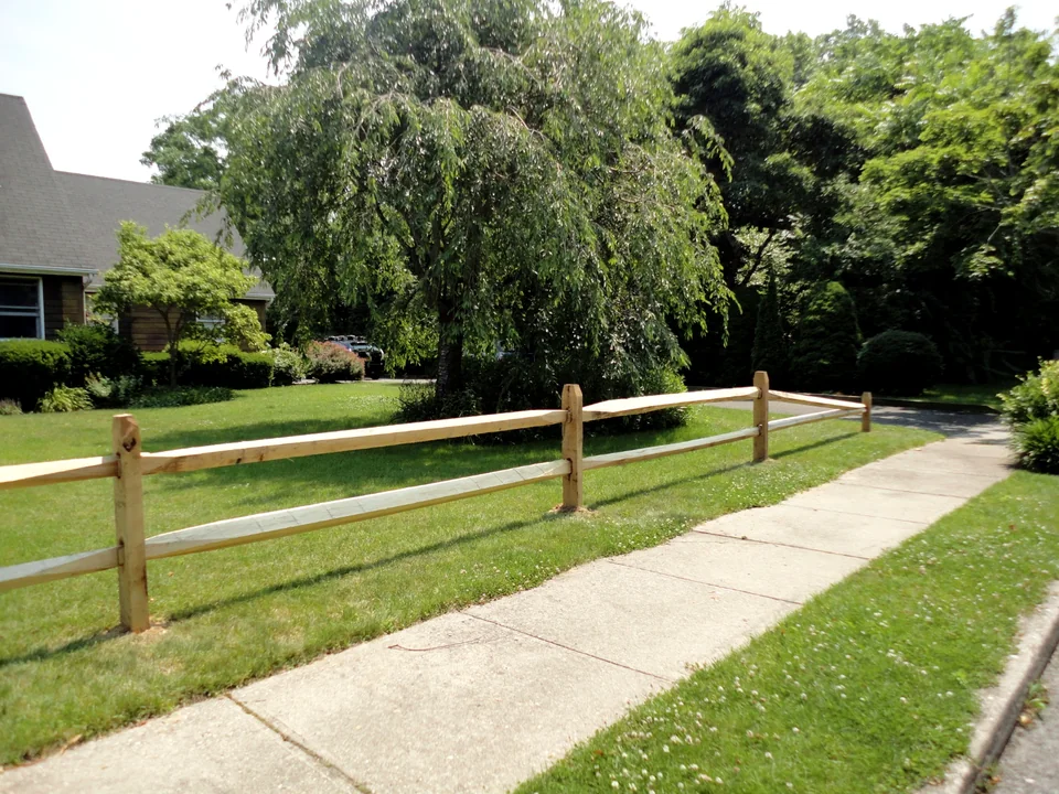 Two-rail locust split rail fence along a sidewalk in Bellport, New York.