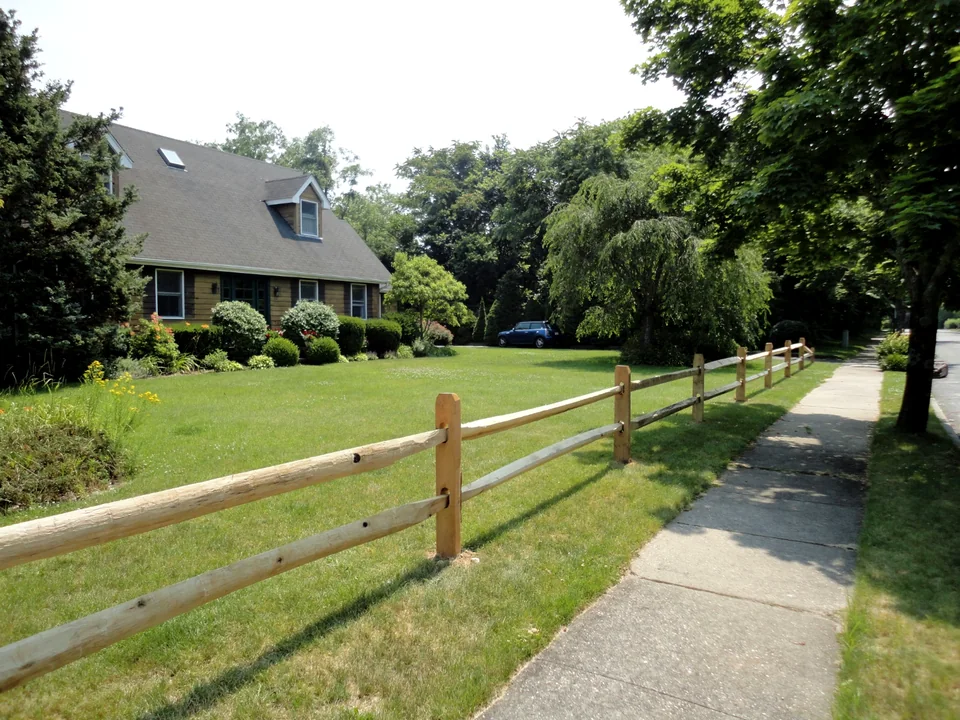 Two-rail split rail fence viewed along the sidewalk in Bellport, New York.