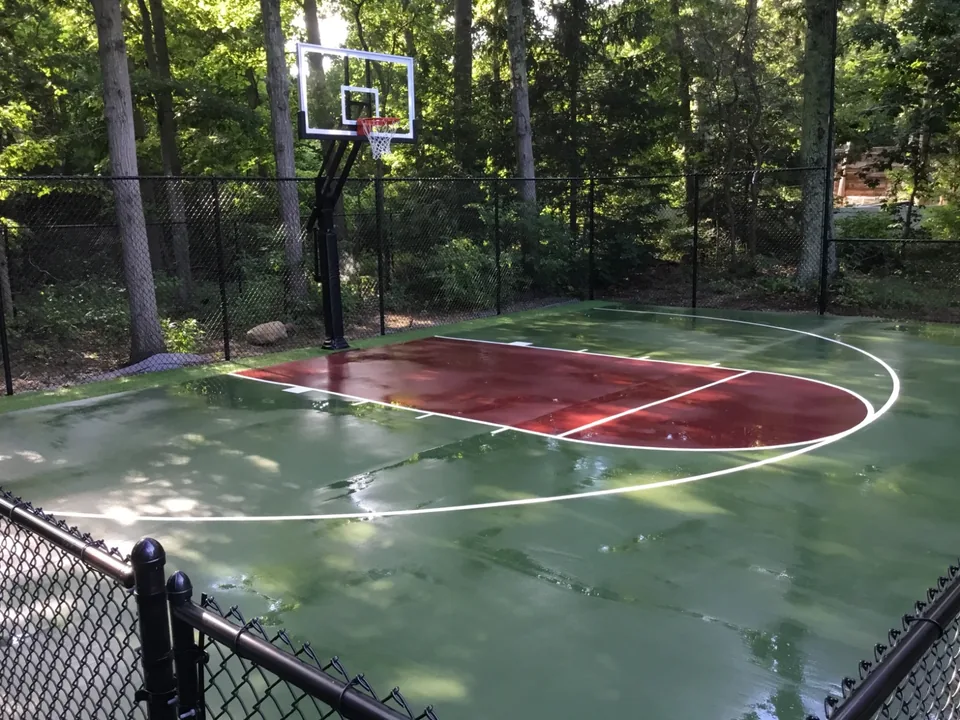 Black chain link fence enclosing a landscaped residential basketball court