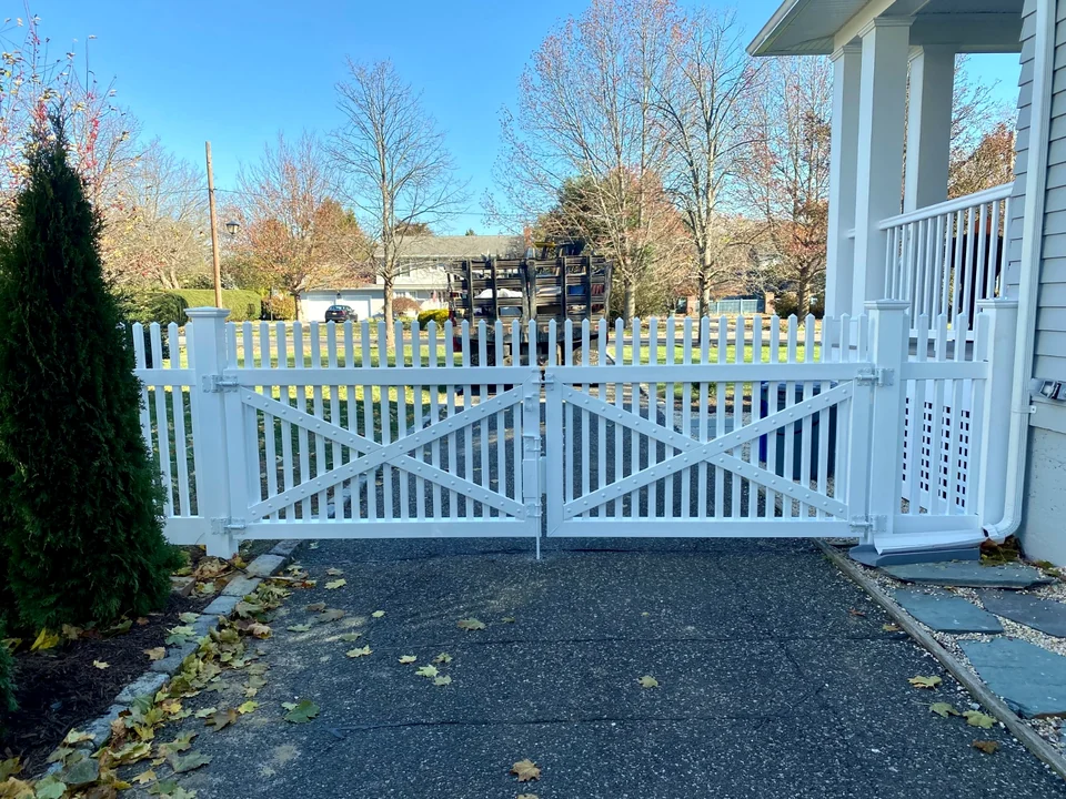 Rear-side view of a white PVC crossbuck double driveway gate in Brightwaters, New York.