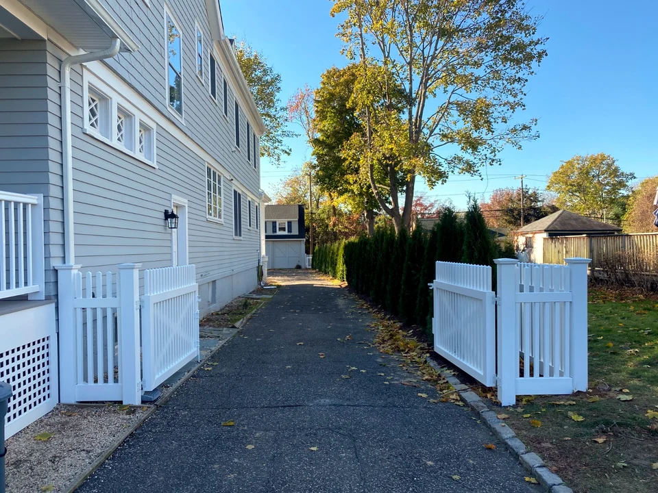 Open white PVC walk gate along the side of a Brightwaters, New York home.